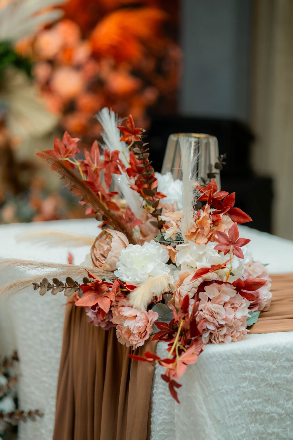 Warm-toned floral arrangement beside a wedding stage