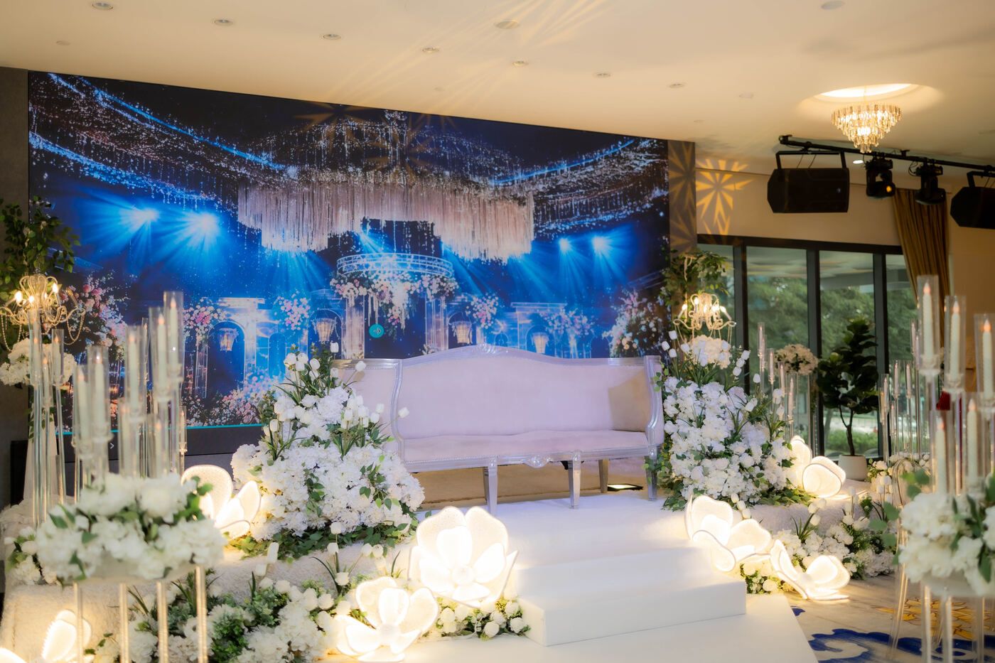 Blue-lit wedding stage with florals at De Villa